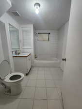 Full bathroom featuring tiled shower / bath, a textured ceiling, and tile patterned floors