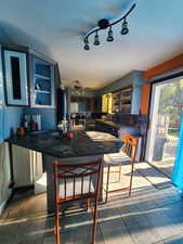 Kitchen featuring dark tile patterned flooring, ceiling fan, kitchen peninsula, and a kitchen breakfast bar