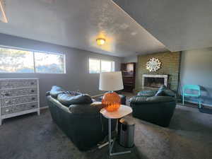 Carpeted living room featuring a fireplace and a textured ceiling