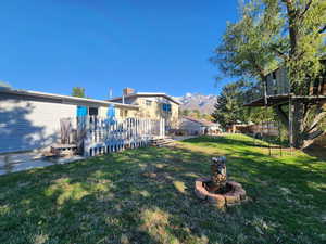 View of yard with a deck with mountain view and an outdoor fire pit