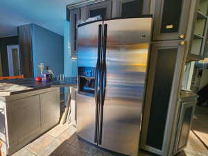 Kitchen featuring green cabinets, stainless steel refrigerator with ice dispenser, and tile patterned flooring