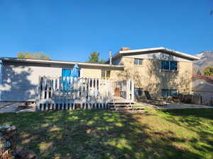 Back of house featuring a patio area, a lawn, and a mountain view