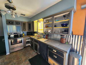 Kitchen featuring sink, electric stove, and tile counters