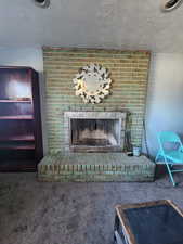 Room details with a brick fireplace, a textured ceiling, and carpet