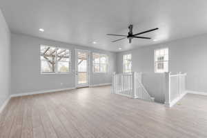 Spare room featuring light wood-type flooring, a textured ceiling, and ceiling fan