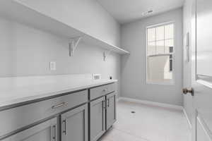 Laundry room with cabinets, light tile patterned flooring, hookup for a washing machine, and hookup for an electric dryer