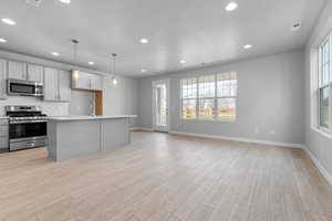 Kitchen with stainless steel appliances, plenty of natural light, a center island with sink, and decorative light fixtures