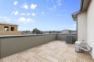 View of patio with central AC unit and a balcony