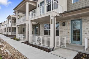 View of exterior entry featuring covered porch and a balcony