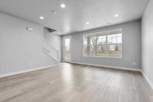 Unfurnished living room with a textured ceiling, light wood-type flooring, and a healthy amount of sunlight