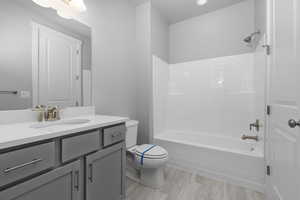 Full bathroom featuring toilet, vanity, hardwood / wood-style floors, and shower / washtub combination