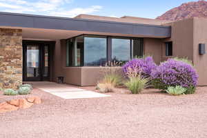 View of exterior entry with stucco siding and stone siding