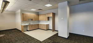 Kitchen with dark carpet, a paneled ceiling, and sink