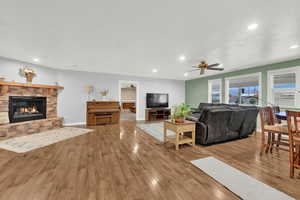 Living room featuring a stone fireplace, light hardwood / wood-style floors, and ceiling fan