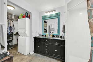 ADU Bathroom with vanity, a textured ceiling, tile patterned flooring, and stacked washer and dryer