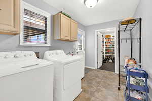 Washroom featuring washing machine and clothes dryer, light tile patterned flooring, cabinets, and a textured ceiling