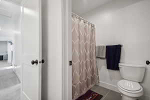 Bathroom featuring tile patterned flooring, toilet, and a shower with curtain