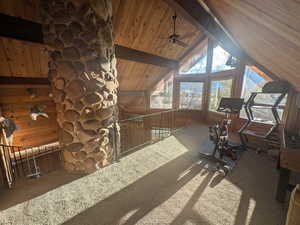 Interior space with carpet floors, wooden walls, wooden ceiling, high vaulted ceiling, and ceiling fan