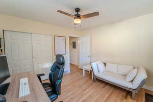 Office with electric panel, ceiling fan, and light hardwood / wood-style flooring