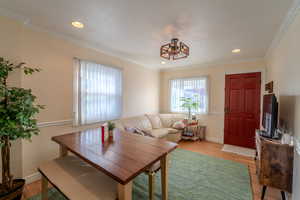 Dining room with light hardwood / wood-style flooring and ornamental molding