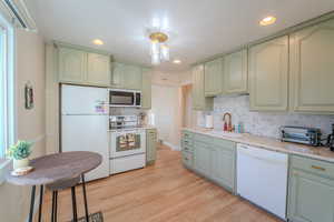 Kitchen featuring tasteful backsplash, white appliances, sink, and light hardwood / wood-style flooring