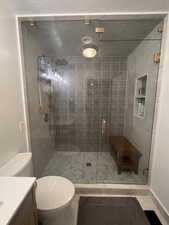 Bathroom featuring walk in shower, tile patterned flooring, vanity, and toilet