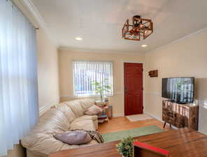 Living room with crown molding and light wood-type flooring