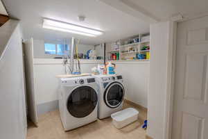 Laundry area with separate washer and dryer and light tile patterned floors