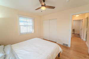 Bedroom with a closet, ceiling fan, and light hardwood / wood-style flooring