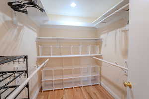 Master bedroom walk-in closet with hardwood flooring