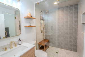 Bathroom featuring toilet, vanity, tile patterned floors, and tiled shower