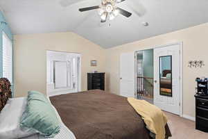 Master bedroom with light colored carpet, ceiling fan, and vaulted ceiling