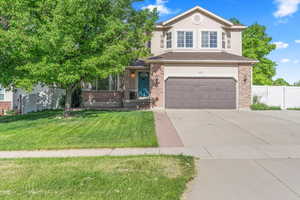 View of front of home with a garage, concrete driveway, and brick siding