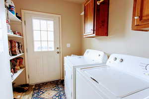 Washroom featuring cabinets and washing machine and clothes dryer