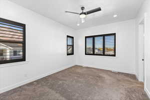 Carpeted empty room featuring ceiling fan