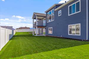 Rear view of house with a yard and a balcony