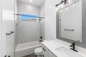 Full bathroom featuring hardwood / wood-style floors, tiled shower / bath, toilet, and vanity