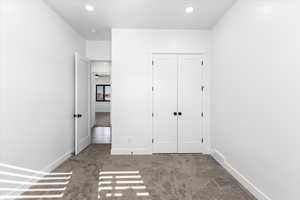 Unfurnished bedroom with light carpet and a closet