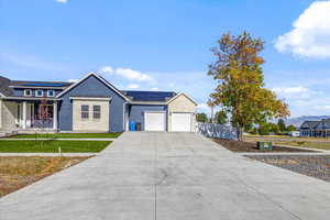 View of front of property with a front lawn, a garage, and solar panels