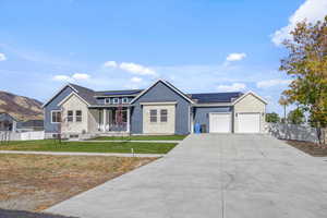 View of front of home with a garage, solar panels, a front yard, and a mountain view