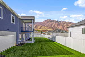 View of yard with a garage, a mountain view, and a balcony