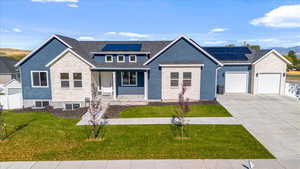 View of front of home with central AC unit, a front yard, solar panels, a garage, and covered porch