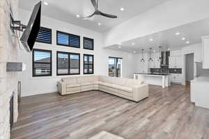 Living room featuring a stone fireplace, light wood-type flooring, and ceiling fan