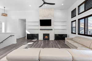 Living room featuring a towering ceiling, a fireplace, dark wood-type flooring, and ceiling fan