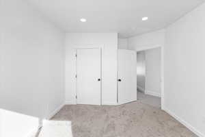 Unfurnished bedroom with light carpet and a closet