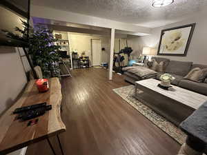 Living room with dark wood-type flooring and a textured ceiling