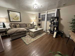 Living room with a textured ceiling and dark hardwood / wood-style floors