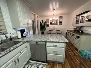 Kitchen with backsplash, dark hardwood / wood-style floors, pendant lighting, dishwasher, and a chandelier