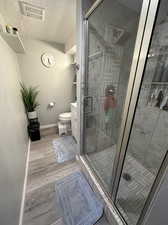 Bathroom with walk in shower, hardwood / wood-style floors, a textured ceiling, and toilet