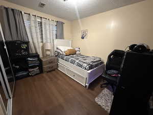 Bedroom featuring dark hardwood / wood-style floors and a textured ceiling